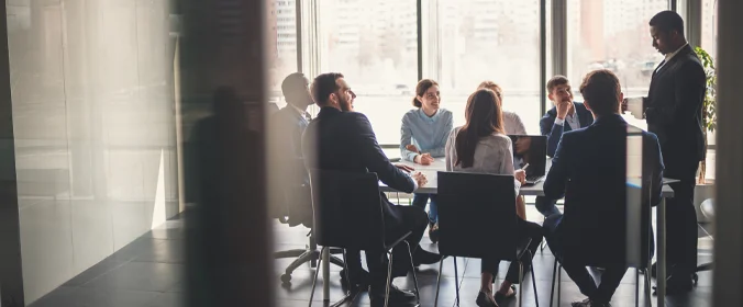 foto de um grupo de executivos em uma mesa, todos de traje formal 